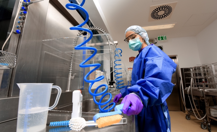 an image of a sterile processing department professional in a hospital wearing full scrubs and working at a cleaning station