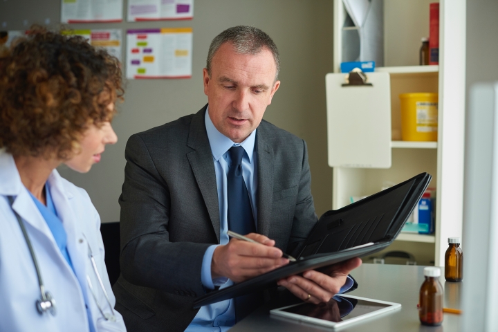 a hospital executive reviewing their organization’s rep-managed supply chain partnership on a tablet