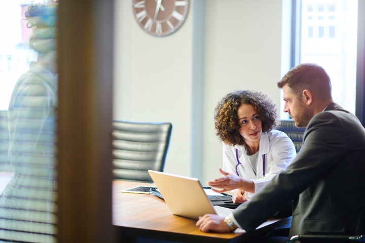 A doctor discussing bill-only workflows with a hospital executive at a conference room desk