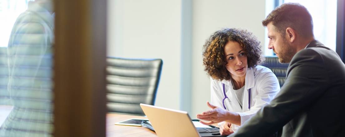 A doctor discussing bill-only workflows with a hospital executive at a conference room desk